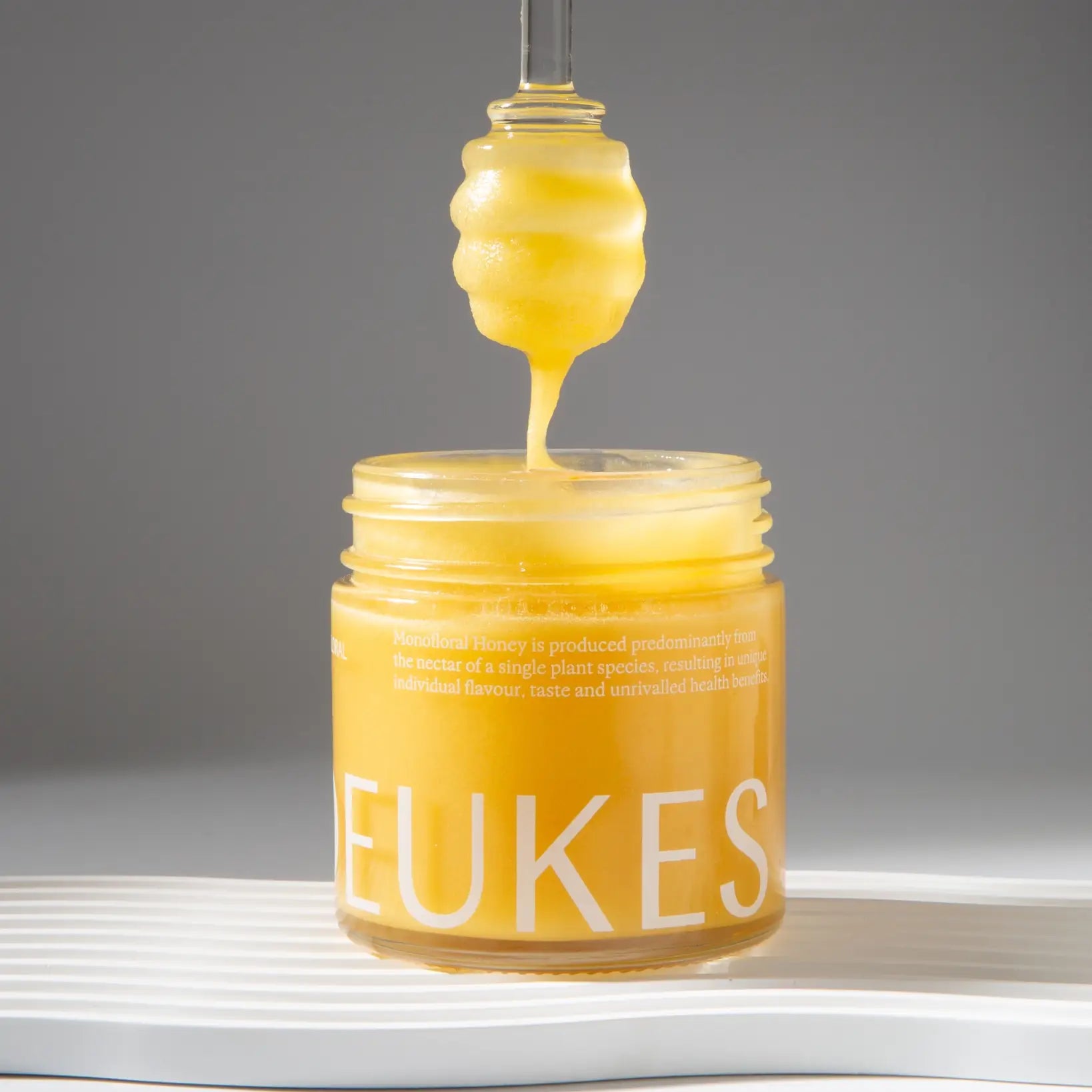 Monofloral sunflower honey in a glass jar with a honey dipper, golden and rich in texture, by Deukes for Tea Lab Pantry
