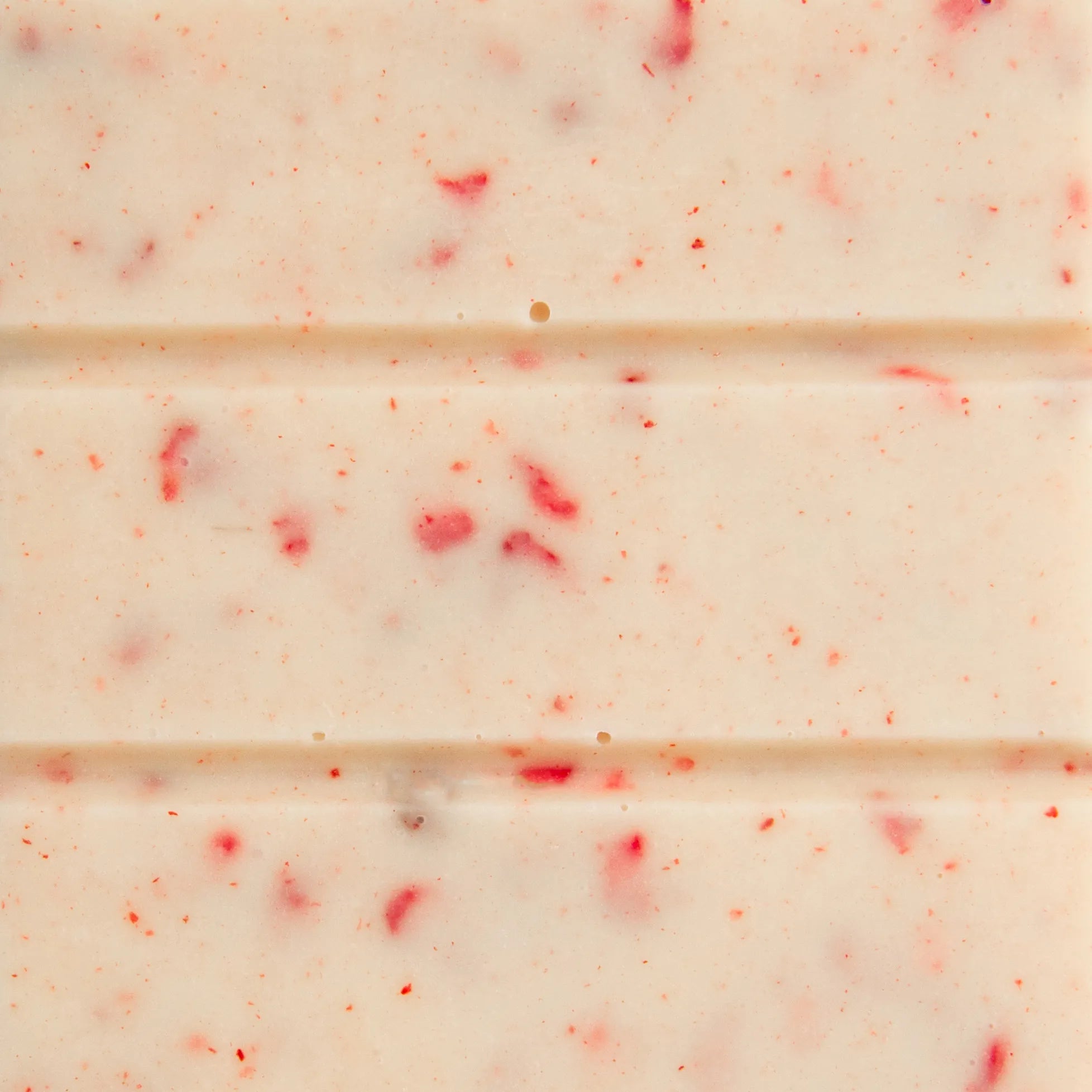 Close-up of white chocolate raspberry bar by The Chocolatier – creamy white chocolate with raspberry pieces, available at Tea Lab